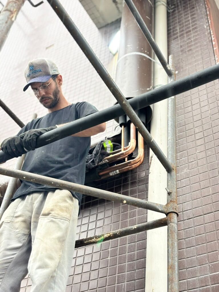Técnico da REFCLIM montando tubulação frigorífica em andaime na fachada